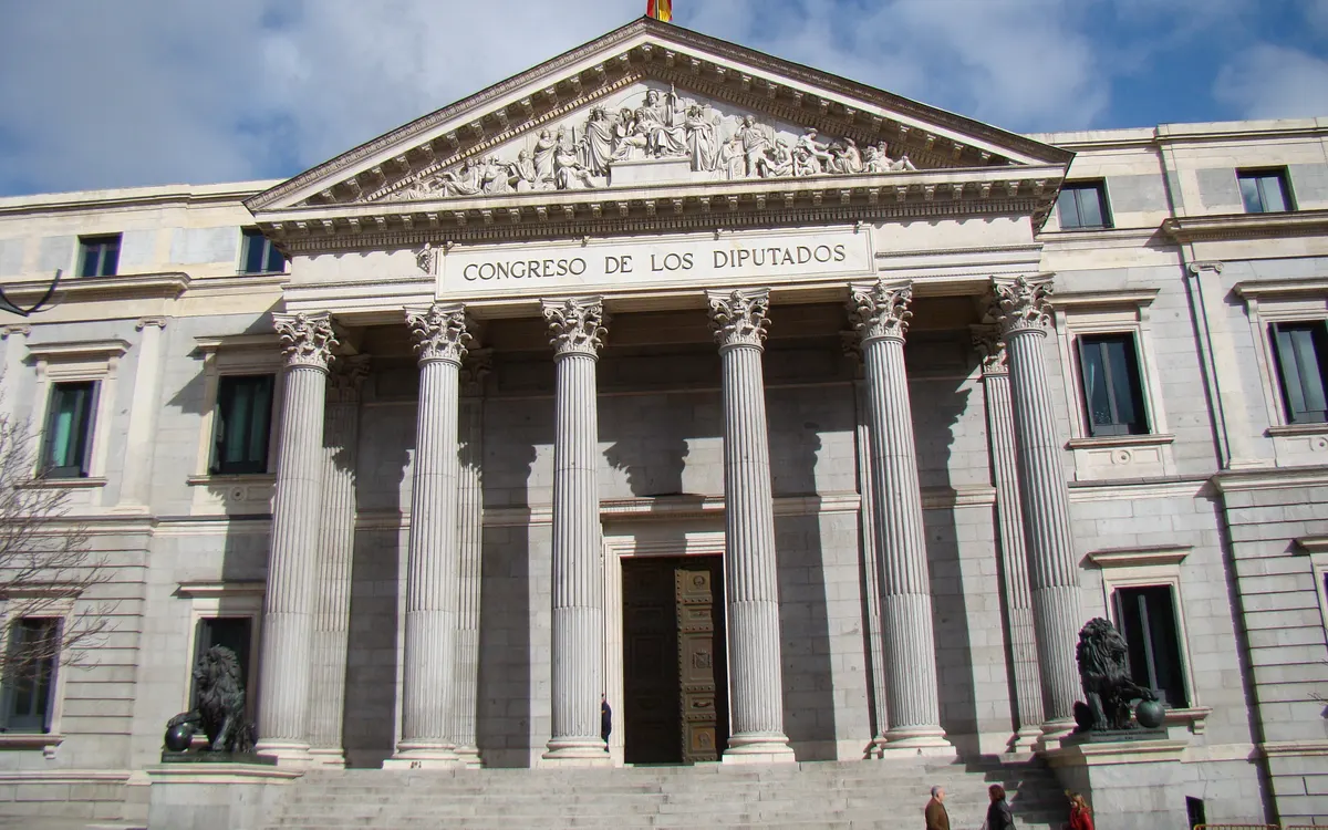 Fachada del Congreso de los Diputados en Madrid con columnas y bandera de España