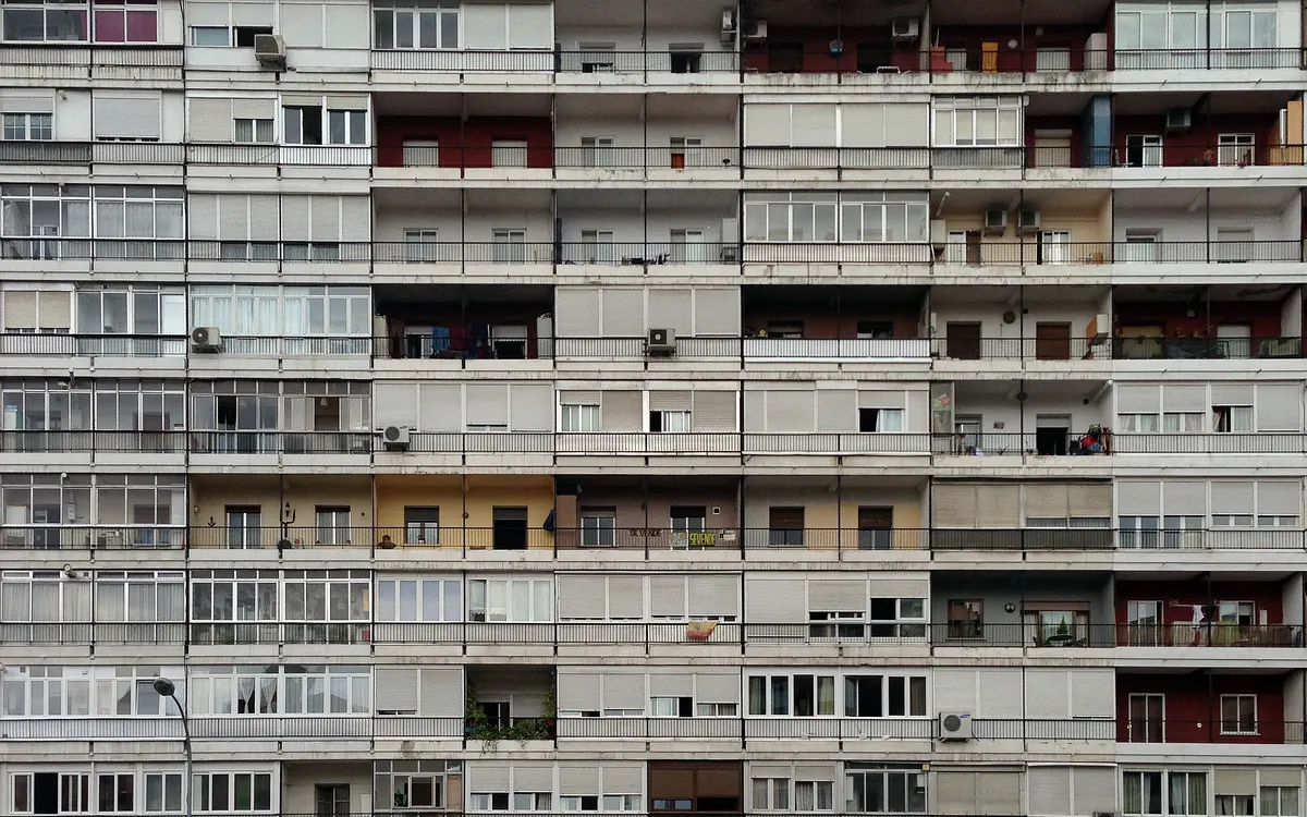 Fachada de un gran bloque de viviendas con balcones y ventanas en Madrid